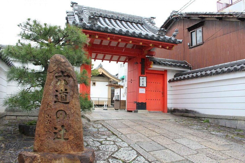A traditional Japanese gate with a stone marker in front. 3