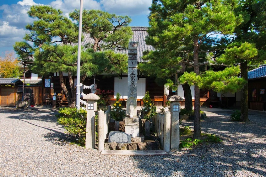 A traditional Japanese cemetery with stone markers, a torii gate, and a building with a tiled roof. 4