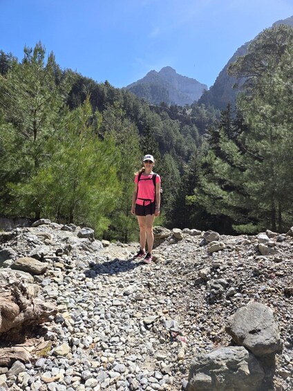 A person hiking on a rocky trail surrounded by trees and mountains. 3