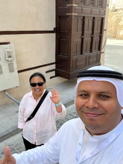 A man in traditional attire and a woman in a light pink shirt waving. 4