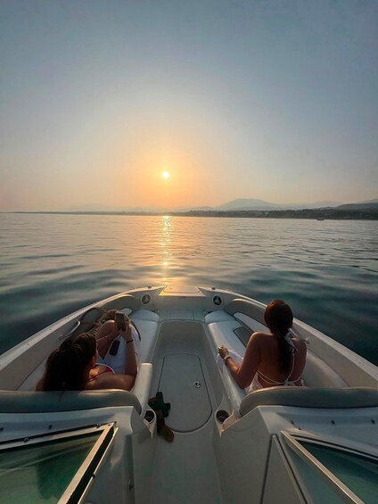 A boat with two people on a calm body of water during sunset. 4