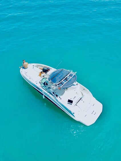 A white yacht with two people on board, floating on turquoise water. 1