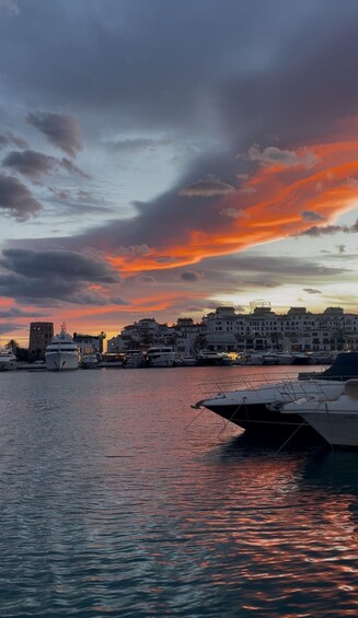 A marina with boats docked, a city skyline, and a sunset sky. 5