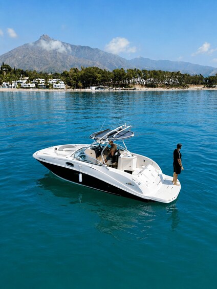 A speedboat on calm water with a mountainous landscape in the background. 2