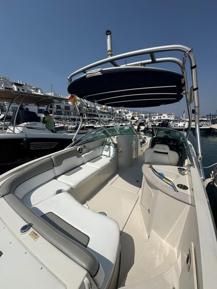 A boat with a covered seating area, a steering wheel, and a water spout. 3