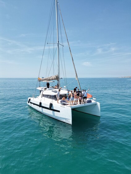 A white catamaran with passengers on a calm sea, under a clear sky. 2