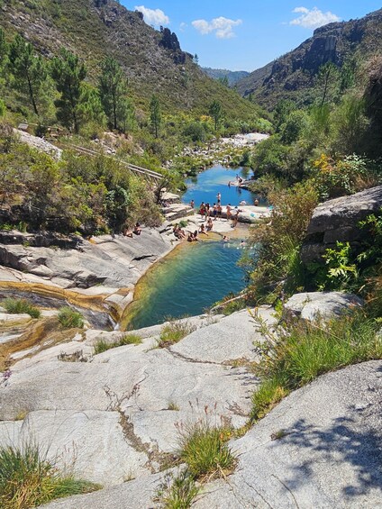 A natural hot spring surrounded by rocky terrain and greenery. 2