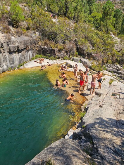 A natural hot spring surrounded by rocky terrain and greenery. 1
