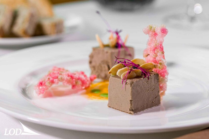 A dessert plate with chocolate mousse cubes, garnished with pink sugar and edible flowers. 5