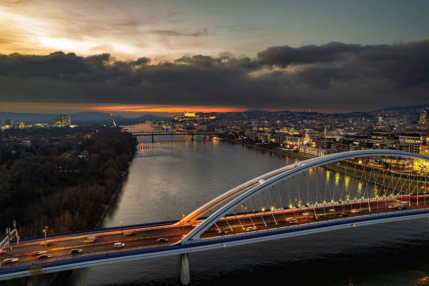 A bridge over a river with city lights and a sunset in the background. 3