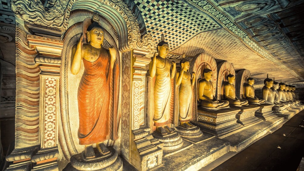 A row of golden Buddha statues in a temple with intricate carvings and a patterned ceiling. 1