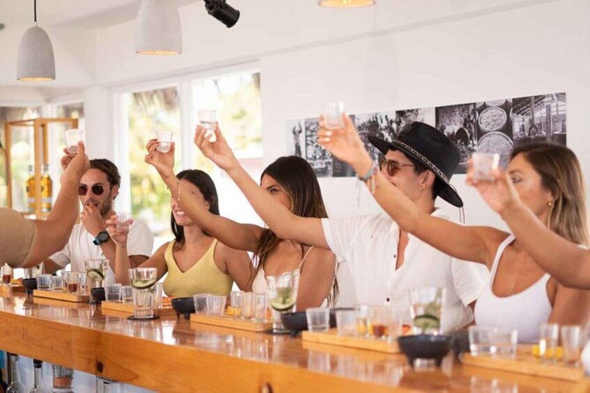A group of people toasting at a bar with various drinks. 1