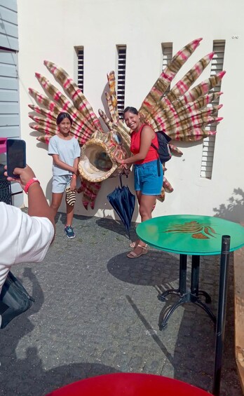 A person taking a photo of a large decorative shell with colorful patterns. 5