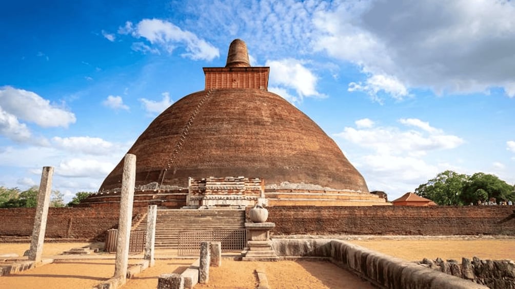 A large, domed structure with a central spire, surrounded by ruins and a clear sky. 2