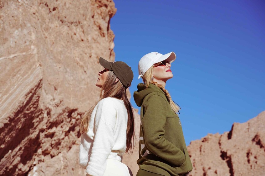 Two people standing on a rocky outcrop with a clear blue sky. 1