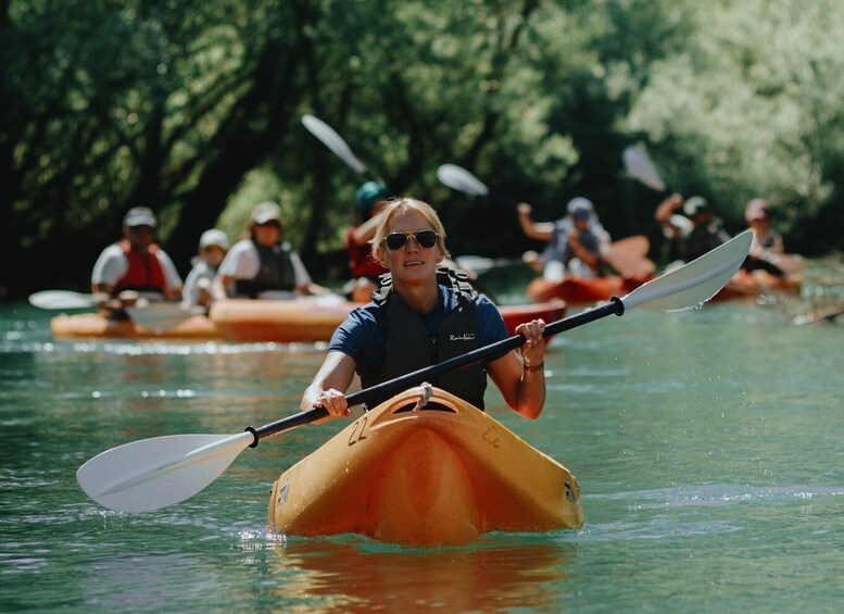 A person kayaking on a river surrounded by other kayakers. 4