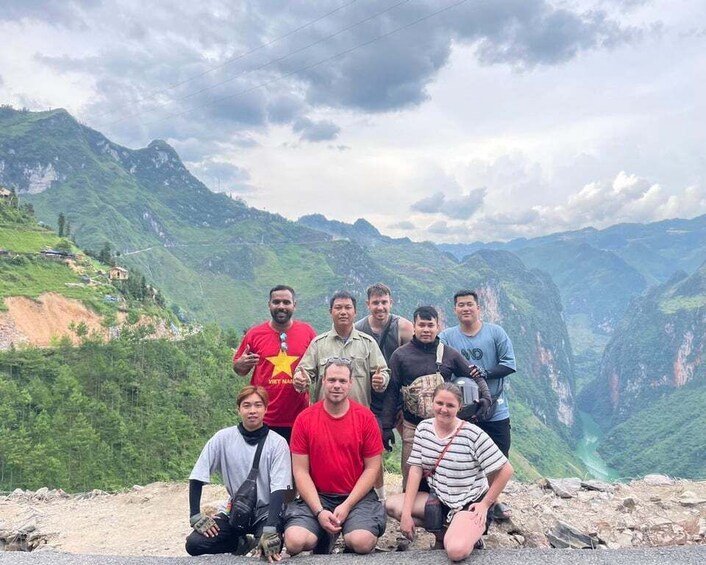 A group of people posing on a mountain ridge with a valley in the background. 2