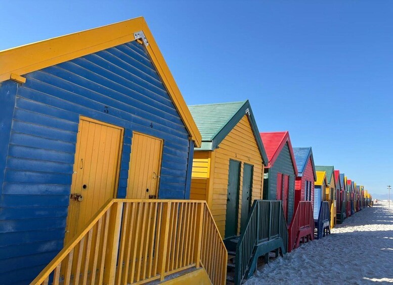 A row of colorful beach huts with wooden railings. 3