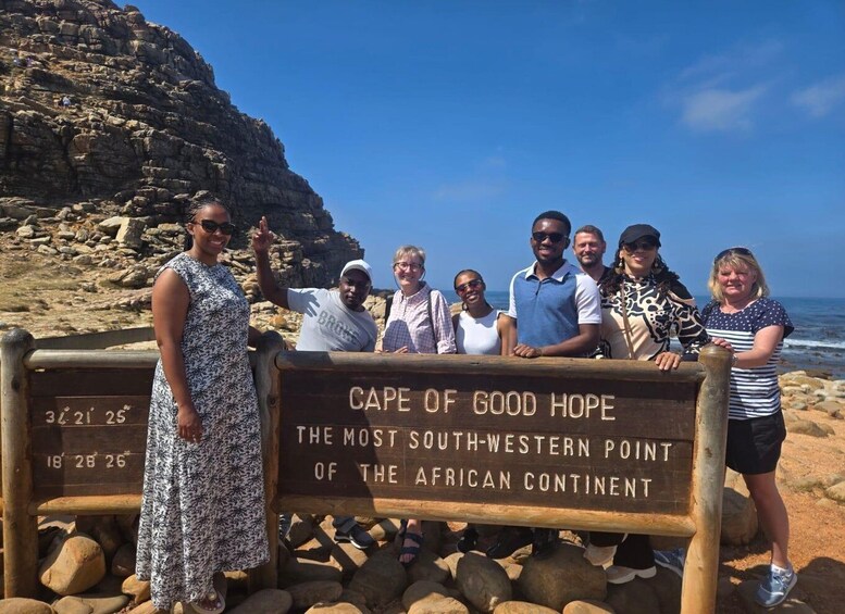 A group of people standing in front of a sign that reads "Cape of Good Hope, the most southwestern point of the African continent." 3