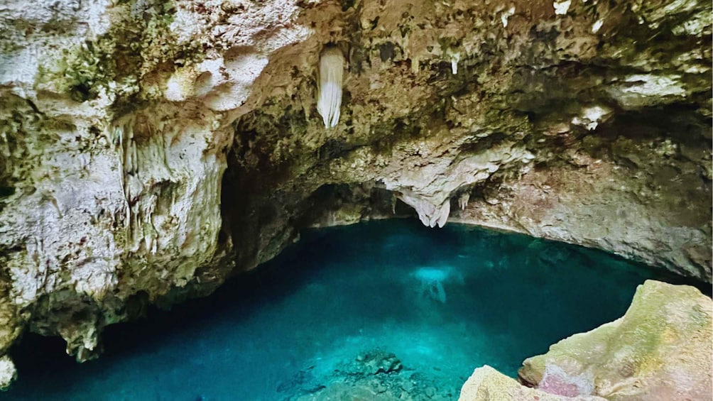 A cave with clear blue water and stalactites. 4