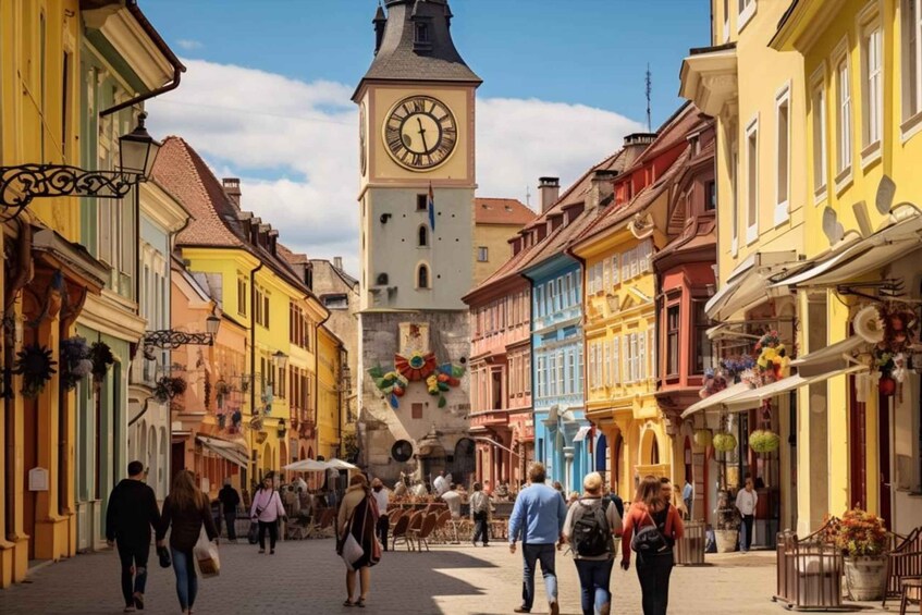 A pedestrian street lined with colorful buildings, a clock tower, and people walking. 2