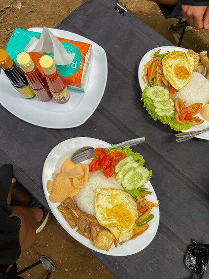 A meal with rice, vegetables, and fried eggs on a plate. 3