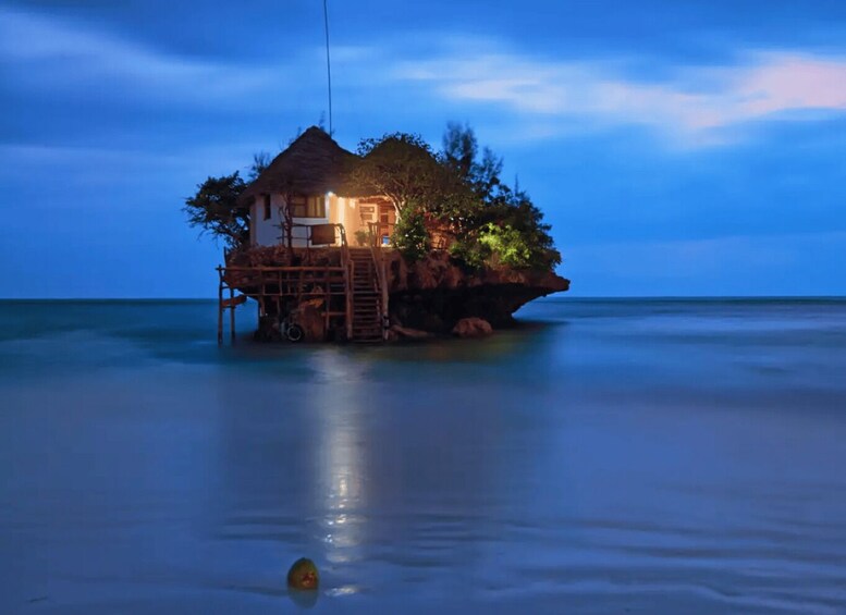 A house on stilts over calm water at dusk. 3