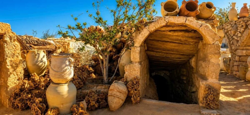 An ancient stone structure with pottery and a tree in the foreground. 3