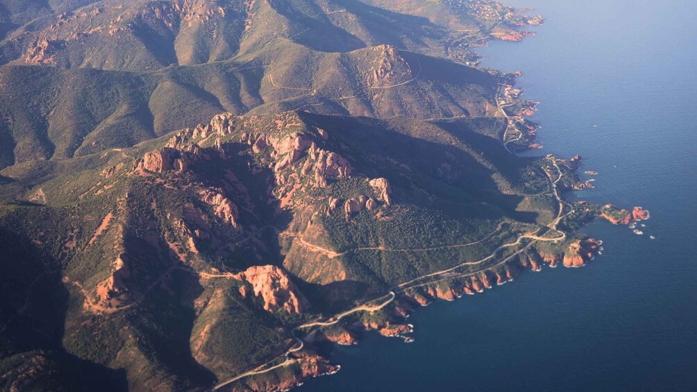 A coastal landscape with rugged mountains, winding roads, and a coastline. 4