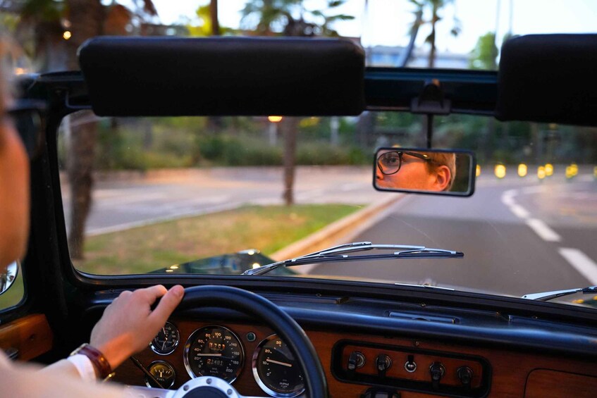 A vintage car's interior with a dashboard, steering wheel, and rearview mirror. 5
