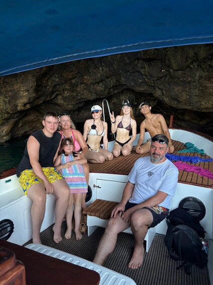 A group of people on a boat with rocky cliffs in the background. 4