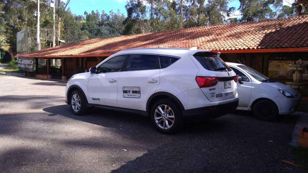 A white SUV parked in front of a building with a tiled roof. 5