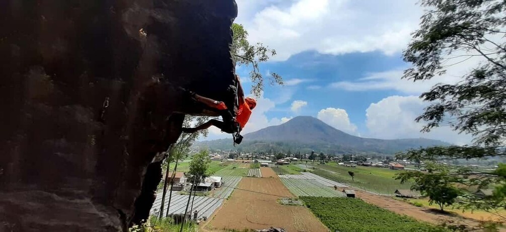 A person rappelling down a cliff with a mountainous landscape in the background. 1
