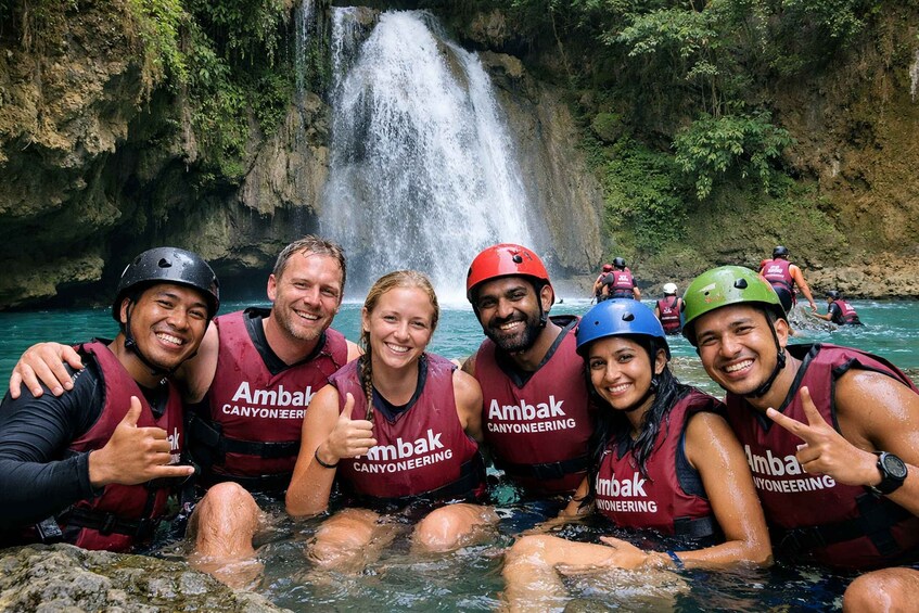 A group of people in water with a waterfall in the background. 4