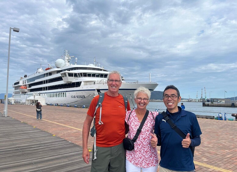 Three people standing on a dock with a large cruise ship named 'Star Seeker' in the background. 2