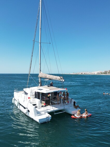 A white sailboat with a cabin and a mast, floating on calm blue waters. 2