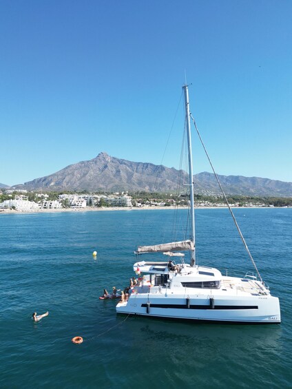 A sailboat named 'BALI' on calm waters with a mountainous backdrop. 3