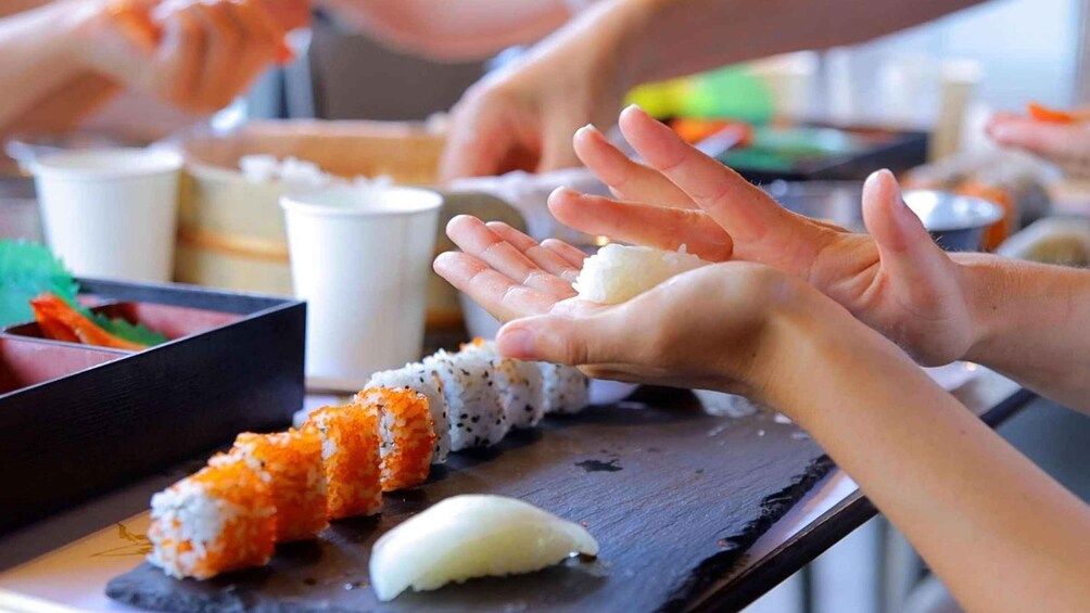People preparing sushi on a table. 1