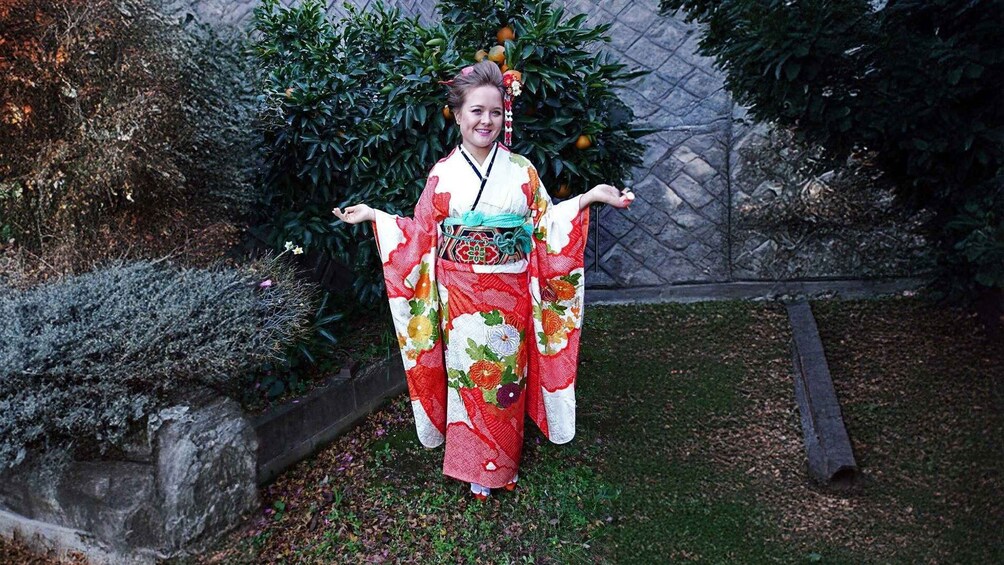 A person in a kimono with floral patterns standing in a garden. 3