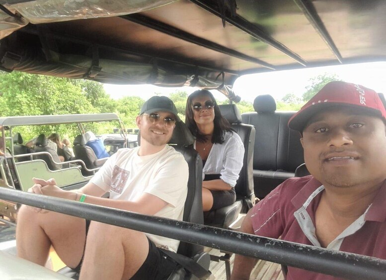 Three people seated in a vehicle with a roof, surrounded by greenery. 5