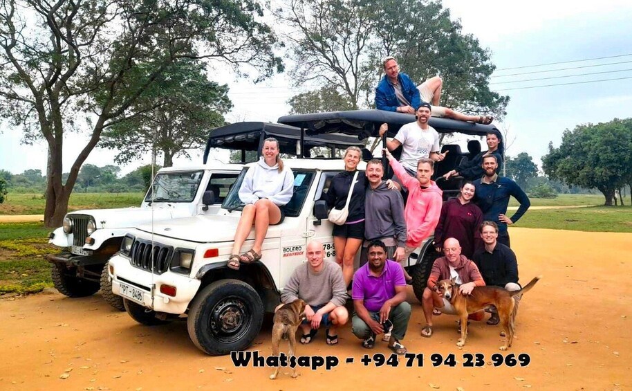 A group of people posing with a white off-road vehicle on a dirt road, surrounded by trees. 1