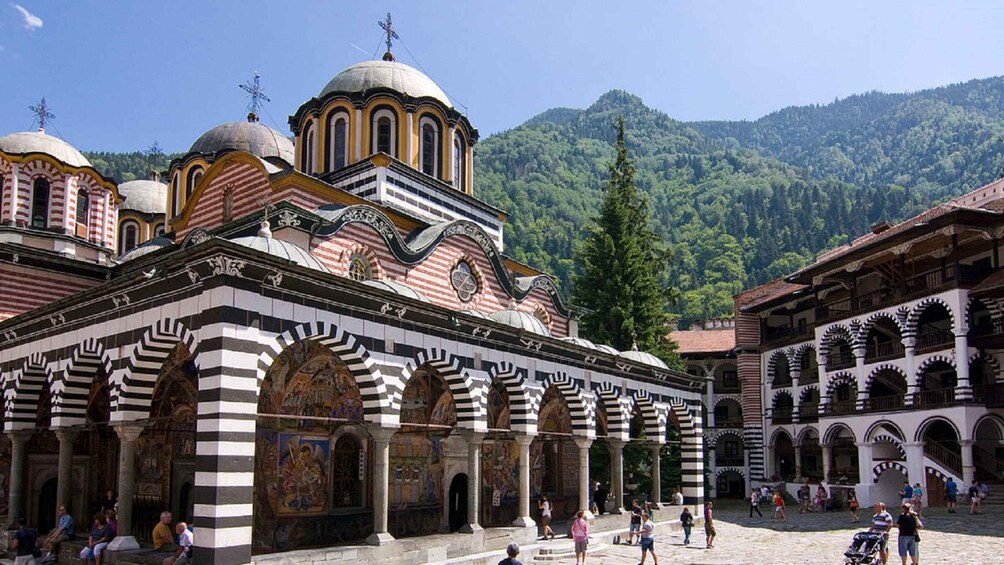 A historic church with multiple domes and arches, surrounded by a mountainous landscape. 1