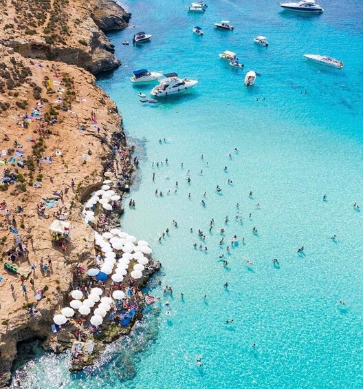 A coastal area with clear turquoise waters, rocky cliffs, and numerous boats. 5