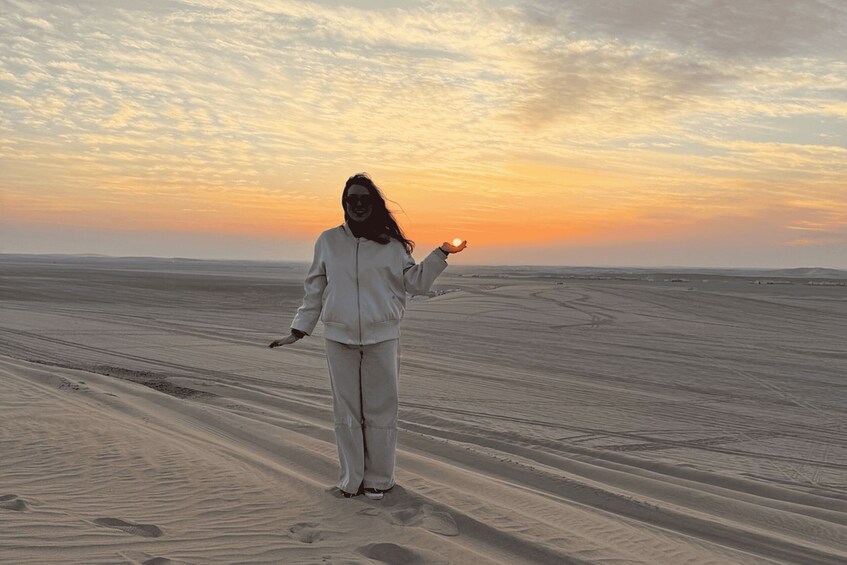 A person standing on a sandy beach with a sunset in the background. 4