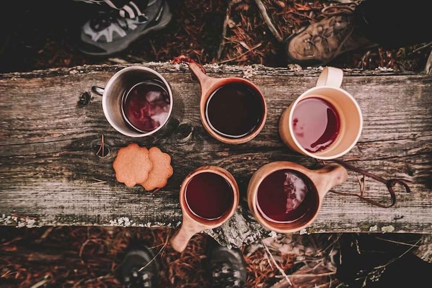 Four wooden cups of tea on a rustic wooden surface. 2