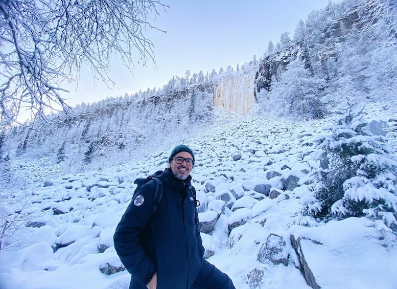 A person in a snowy forest with snow-covered trees and rocks. 3