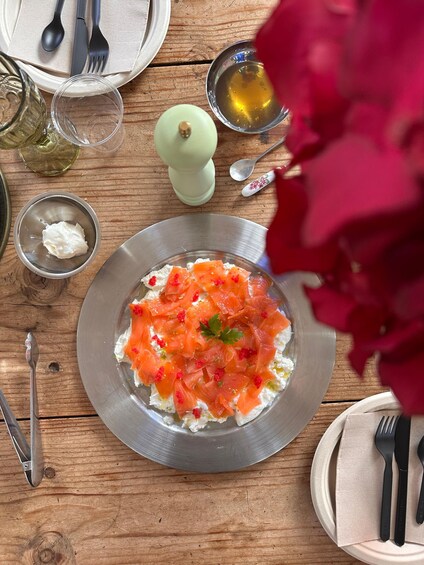 A plate of salmon and cream cheese salad with a sprig of parsley, surrounded by dining utensils and a wooden table. 5