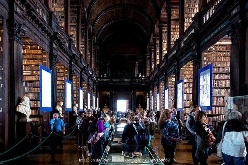 A large, ornate library interior with high wooden bookshelves and a central aisle. 2