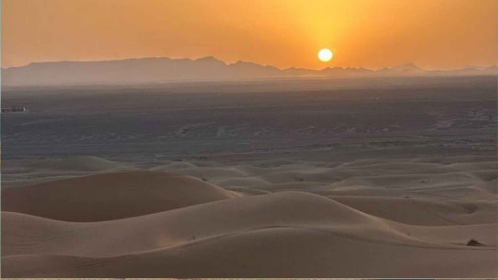 A desert landscape with sand dunes and a setting sun. 5