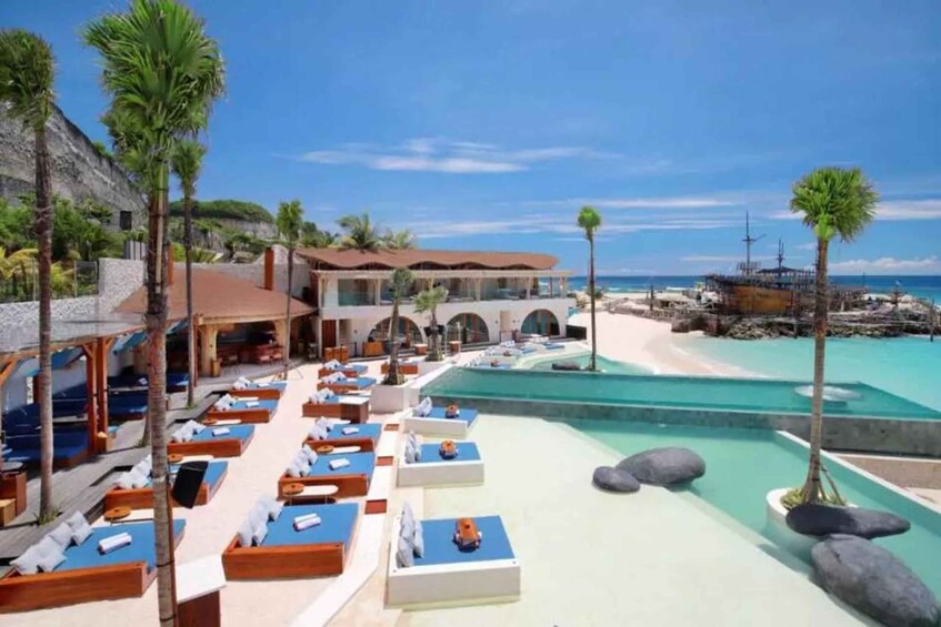 A resort with sun loungers by a pool and a beach. 1